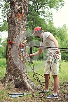 Man prepares the equipment fixes secures the rope to the tree