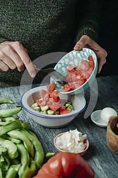 man prepares a spanish salad with broad beans