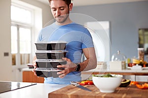 Man Preparing Batch Of Healthy Meals At Home In Kitchen