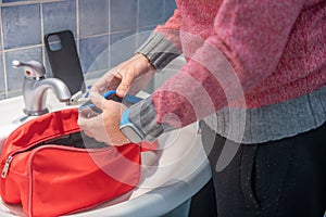 Man is preparing the beauty case in the bathroom. Packing toiletries into a wash bag