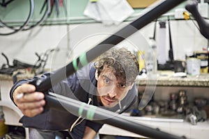 Man preparing a bicycle frame with masking tape to paint it in his workshop