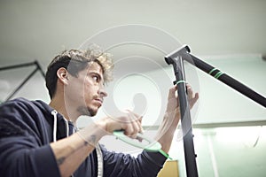 Man preparing a bicycle frame with masking tape to paint it in his workshop