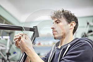 Man preparing a bicycle frame with masking tape to paint it in his workshop