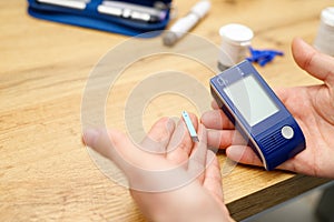 Man preparing for checking blood sugar level with glucometer by himself, treatment of diabetes concept.