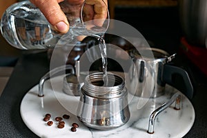 Man preparing classic Italian coffee in the mocha in the kitchen, pouring water into the coffee maker. Coffee brake. Morning habit