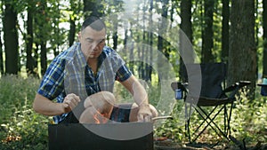 Man preparing firewood for a barbecue in a forest. Casual outdoor activity. Camping and survival skills concept. Design