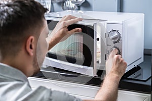 Man Preparing Food In Microwave Oven