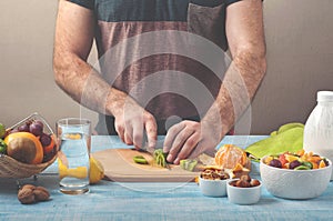 Man preparing a fruit salad in the kitchen at home