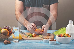 Man preparing a fruit salad in the kitchen at home