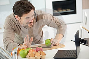 man preparing fruit while waving to laptop screen