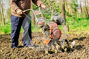 Man preparing garden soil with cultivator tiller