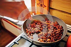 Man preparing nuts in frying pan at home kitchen