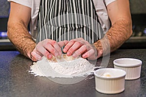 Man preparing pizza dough on black granite table