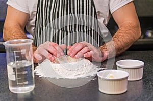 Man preparing pizza dough on black granite table