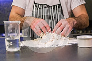 Man preparing pizza dough on black granite table