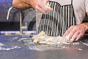 Man preparing pizza dough on black granite table