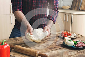 Man preparing pizza in home kitchen on wooden table