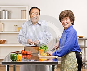 Man preparing salad with wife in kitchen