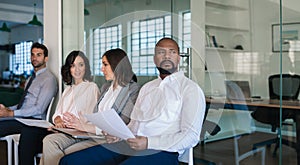 Man preparing to be interviewed while waiting with other applicants