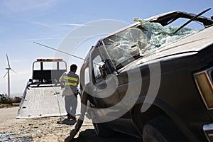 Man Preparing To Lift Crashed Car Onto Tow Truck