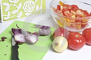 A man is preparing a vegetable salad. He cuts the onion on a cutting board.