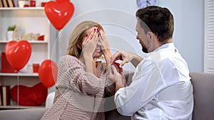 Man presenting beloved lady with closed eyes precious ring, proposal marriage