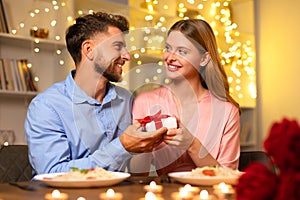 Man presents gift to woman, sharing a joyful moment at dinner