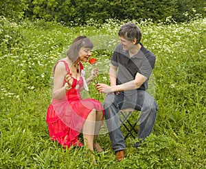 Man presents woman red rose