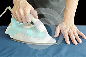 man pressing automatic electric iron to shirt on ironing board