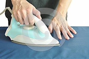 Man pressing blue automatic electric iron to shirt on ironing board