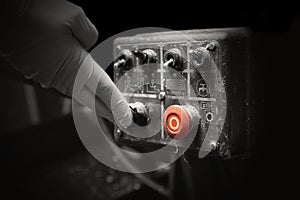Man pressing button on an industrial machine control panel. With lighting effect