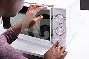 Man Pressing Button Of Microwave Oven