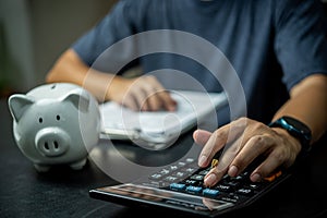 man pressing the calculator holding piggy bank.Investment, accounting, planning financial and banking concept