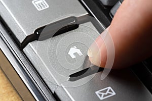 Man pressing a home button, finger pushing home symbol shortcut key on a keyboard, object closeup, real estate business mortgage