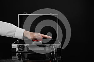 Man pressing red button of nuclear weapon on black background, closeup with space for text. War concept