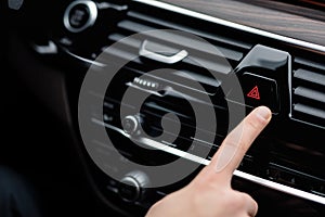 Man pressing red triangle car hazard light button