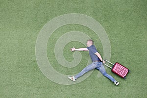 Man pretend to run on green summer grass with suitcase