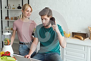 man pretending talking on eggplant at table with laptop and girlfriend