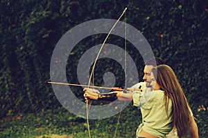 Man and pretty woman shooting with bow and arrow