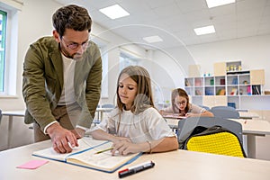 Man primary school teacher in classroom with pupils.