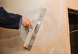 Man is priming a surface with a palett knife.  Maintenance repair works renovation in the flat. Restoration indoors. Concrete