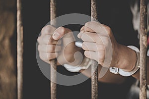 Man in prison hands of behind hold Steel cage jail bars, Male prisoners were severely strained in the dark prison, Imprisonment