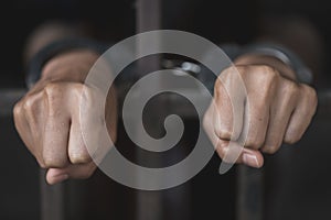 Man in prison hands of behind hold Steel cage jail bars, Male prisoners were severely strained in the dark prison, violence,