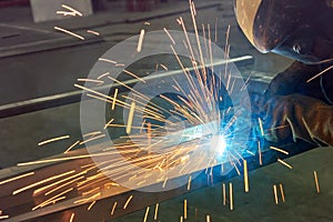 Man processes metal with gas electric welding