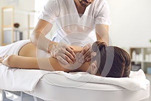 Man professional chiropractor or masseur making massage of back and shoulders for woman in clinic