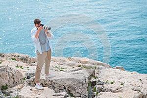 man with professional dslr camera taking picture of seashore