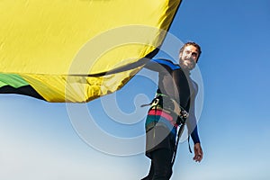 Man professional surfer standing on the sandy beach with his kite