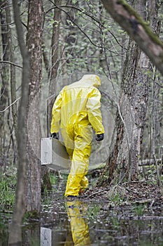 Man  in professional uniform with silver suitcase walking in contaminated floods area photo