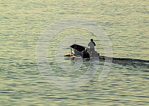 Man propelling a boat through the tranquil waters of the ocean.