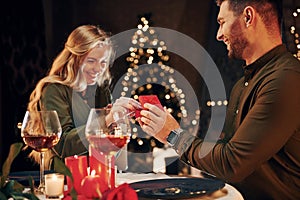 Man proposing a beautiful woman to marry him in an elegant restaurant. Young lovely couple have romantic dinner indoors together